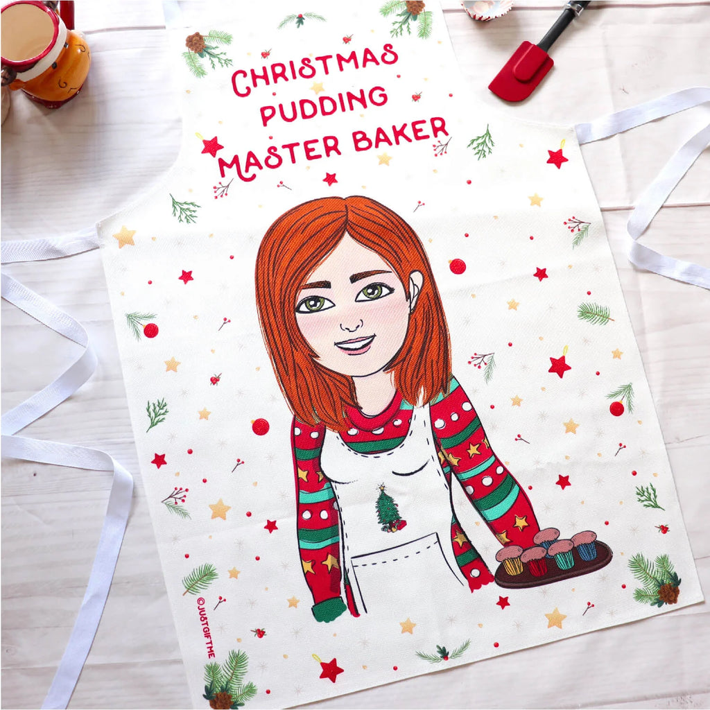 Personalised cooking apron for women with a Christmas theme personalised with a cartoon wearing a christmas jumper and apron and holding a tray with cupcakes. At the top it says Christmas Pudding Master Baker